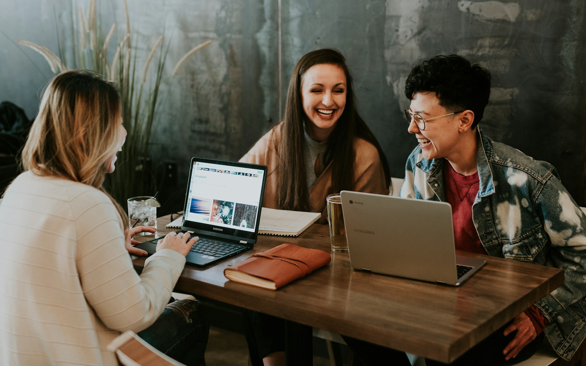three people sitting in front of table laughing together